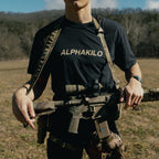 Person wearing an AlphaKilo shirt with tactical gear in a field