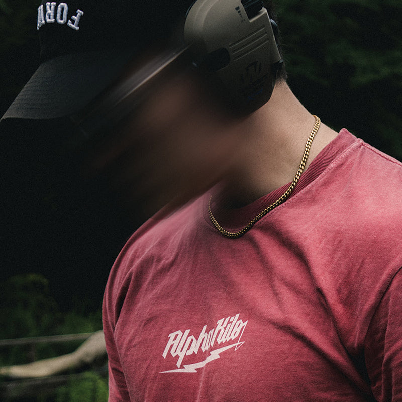 Person wearing a red t-shirt with a logo, standing outdoors with blurred face
